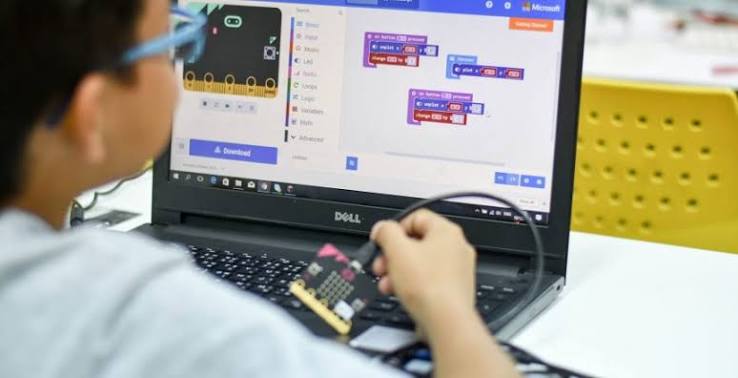 Student learning to code with a micro:bit and laptop